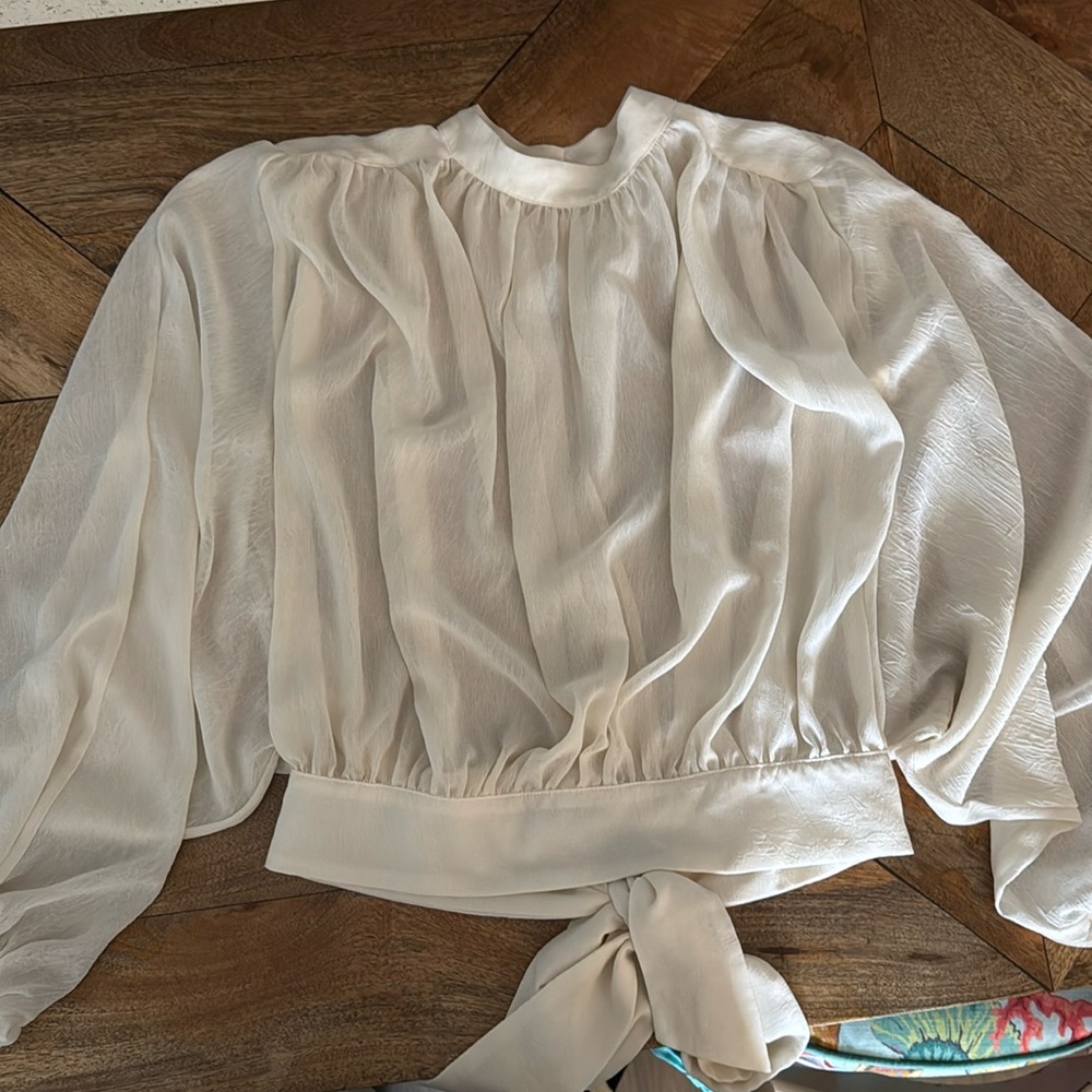 Sheer cream colored blouse with open back and bow detail